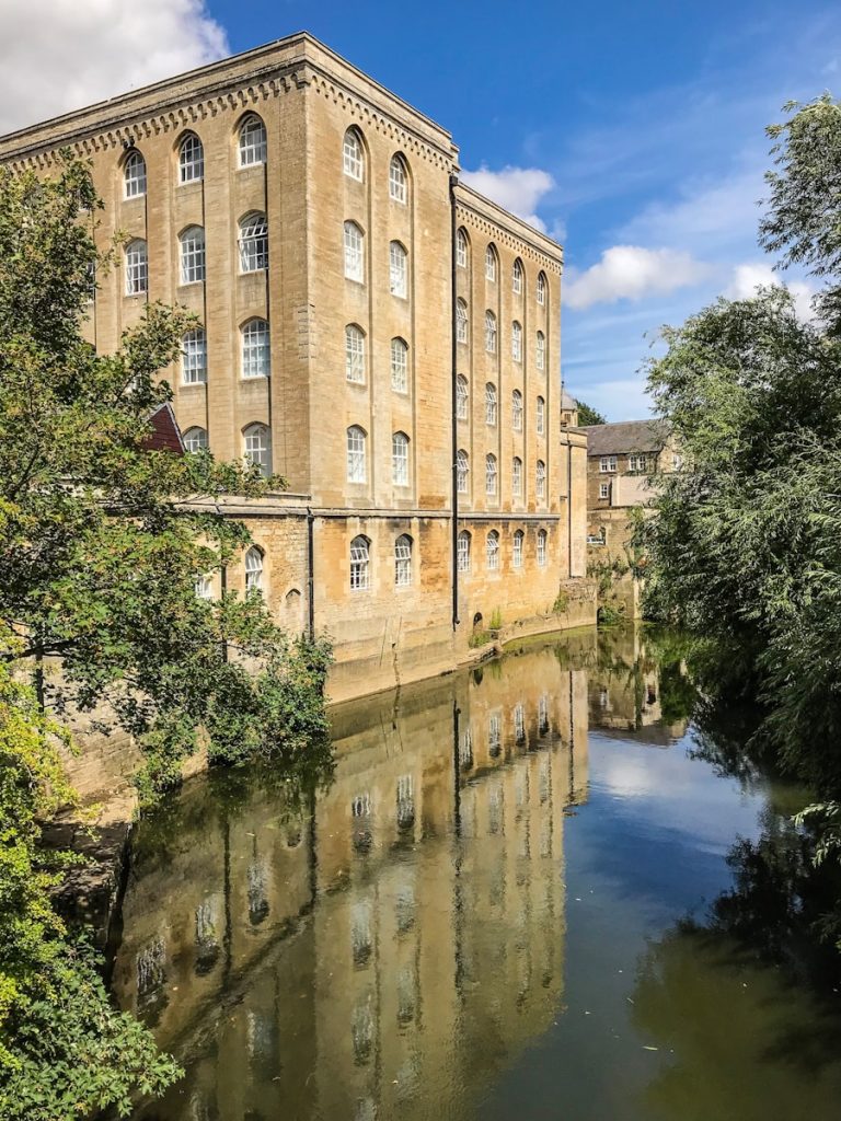 brown concrete building near grey body of water and trees at daytime - saltaire bradford filming location
